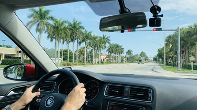 A red convertible car hire driving down Ocean Drive in Miami on a sunny day past art deco buildings