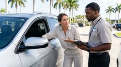 Man inspecting the front seat interior of a car rental vehicle at a sunny Florida parking lot
