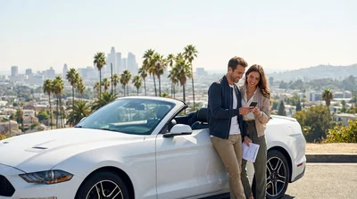 Driver navigating a modern car rental down a sunny palm-lined road in Los Angeles