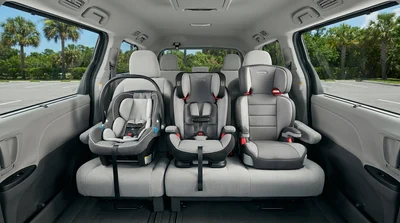 Three child seats installed across the back row of a spacious SUV car rental in Florida