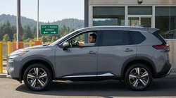 A silver car rental driving on a scenic forested highway in New York
