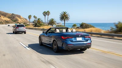 Driver adjusting adaptive cruise control on the steering wheel of a car rental on a California highway