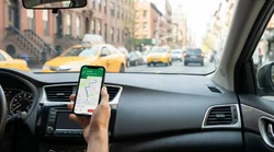 Driver holding a smartphone with a navigation app inside a car rental on a New York street