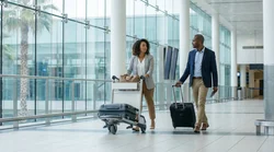 Passengers with luggage walking through the arrivals terminal toward a car rental desk at Miami Airport