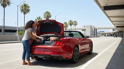 Traveler packing suitcases into the trunk of a car rental at LAX in Los Angeles
