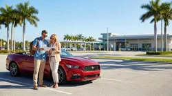 White car rental parked beside tall palm trees on a sunny coastal highway in Florida