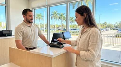 Customer inserting a credit card into a payment terminal at a car hire counter in Florida