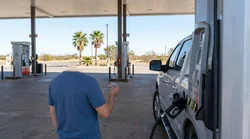 Person paying for gas with a credit card next to a car rental in Texas