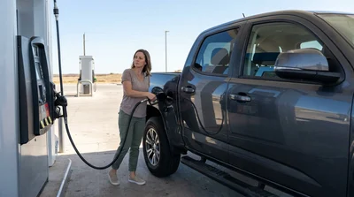 Driver pumping gas into a white car rental at a gas station in Texas