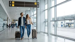 Passengers walking through Terminal A arrivals at a New York airport with overhead signs for the car hire center