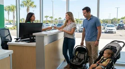 Father buckling a child into a safety seat inside a car rental vehicle parked in sunny Orlando