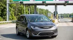 White car rental driving on the Pennsylvania Turnpike approaching a highway toll plaza