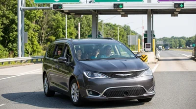 White car rental driving on the Pennsylvania Turnpike approaching a highway toll plaza