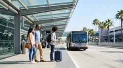 Hola car hire shuttle bus waiting at the LAX Terminal 3 pickup stop in Los Angeles
