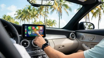 Close-up of an Apple CarPlay screen on a car rental dashboard with a sunny Miami street visible through the windshield