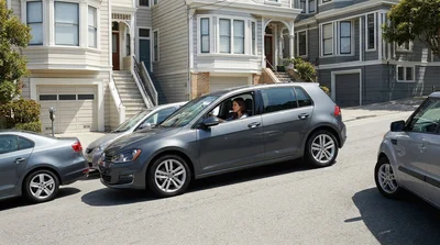 Compact car rental squeezed into a tight parking spot on a steep hill in San Francisco