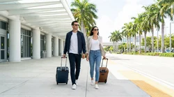 Sunny exterior of the Miami Brightline station with a passenger walking toward a car rental pickup