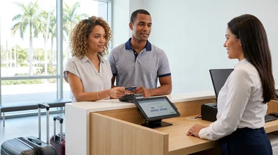 Traveler tapping a credit card on a payment terminal at a car rental desk in Miami