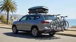 White SUV car rental with a loaded bike rack parked along a scenic coastal highway in California