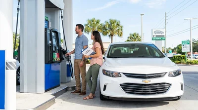 Person checking the dashboard fuel gauge inside a vehicle at an Orlando car rental lot