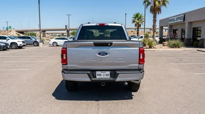 White car rental SUV towing a small travel trailer on a sunny paved highway in Texas