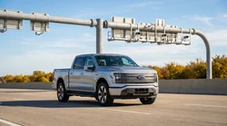 White car rental driving on a sunny Texas highway approaching an electronic toll gantry