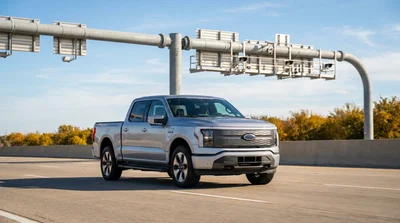 White car rental driving on a sunny Texas highway approaching an electronic toll gantry