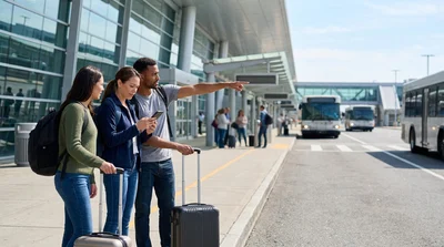 Travelers boarding a car hire shuttle bus with luggage outside an airport terminal in New York