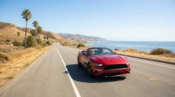 A person driving a car rental along a scenic coastal highway in California