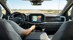 Car rental dashboard showing a connected smartphone screen on a Texas highway