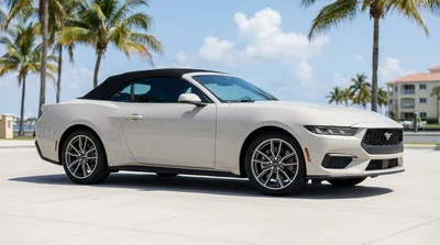 Red convertible car rental with the top down driving along a sunny coastal road in Florida