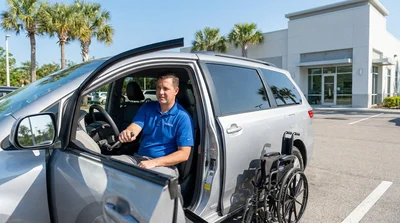 Close-up of a driver using hand controls inside an accessible car rental on a sunny road in Florida