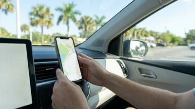 Smartphone attached to a dashboard phone holder displaying GPS navigation inside a Florida car rental
