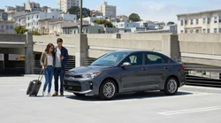A traveler receiving keys from an agent at a car rental desk in San Francisco