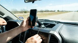 Smartphone in a dashboard mount with a charging cable inside a car rental on a Texas highway