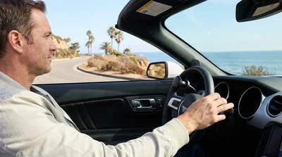 Driver's hands operating adaptive hand controls in a car rental on a sunny street in California