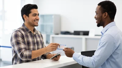 Mexican customer presents driver's license for Texas car hire pick-up at counter.