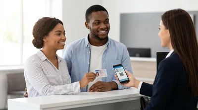 Customer shows both a physical driver's license and a digital phone ID to a car hire agent in Texas.