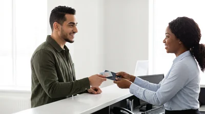 Customer presents license and passport to an agent for New York car rental pickup.