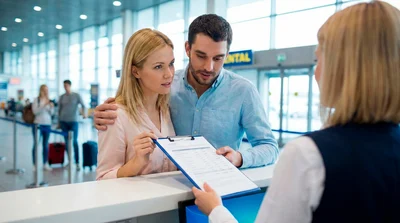 Couple discussing rental car rates with an agent at the Miami Airport rental counter.